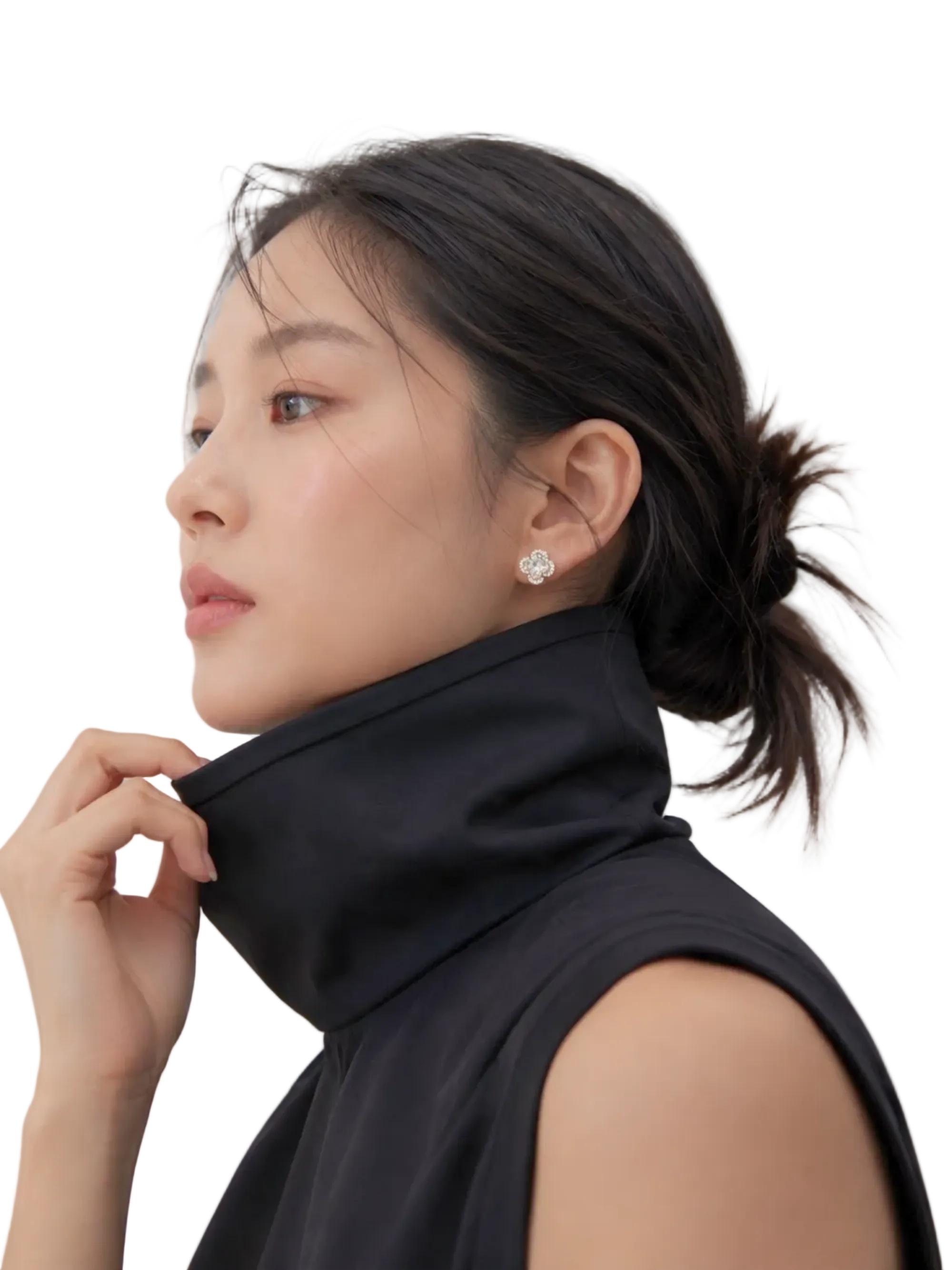 A woman in a black sleeveless high-neck top wearing a sparkling diamond stud earring, shown in profile against a light gray background.