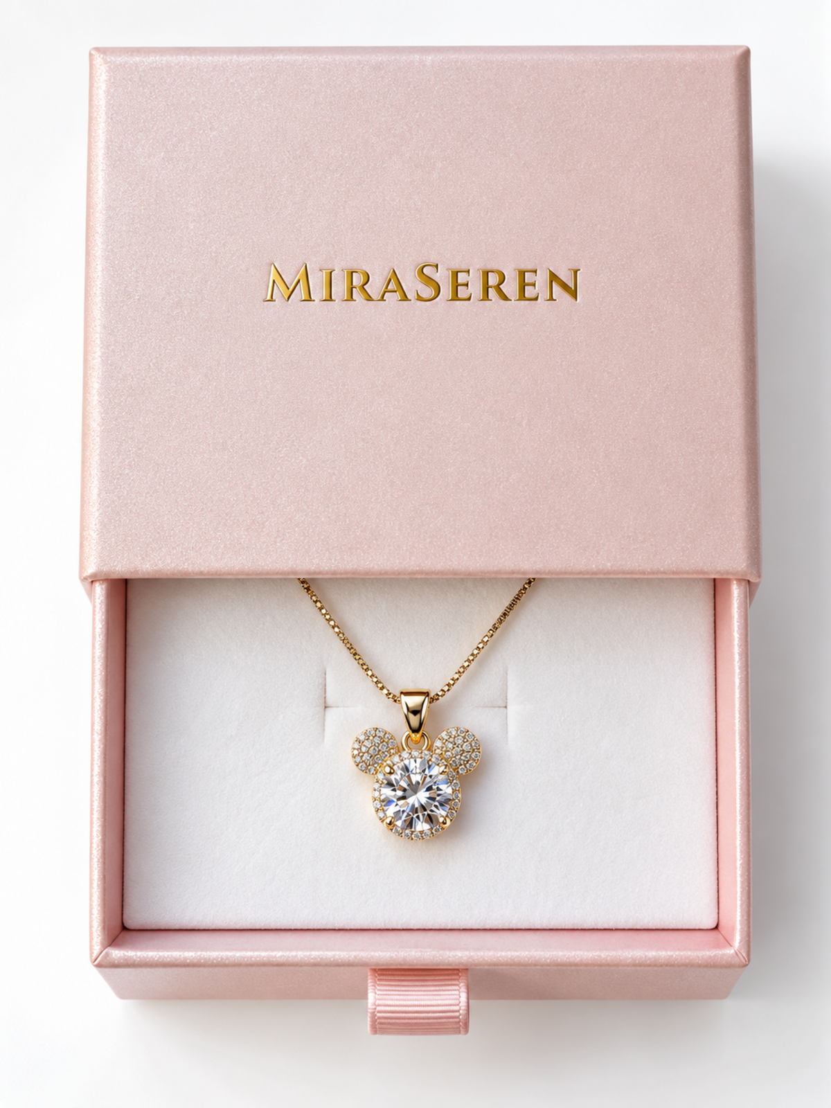 A gold pendant necklace with a clear round gemstone and sparkling side stones, displayed inside an open pink Miraseren gift box on a white insert.