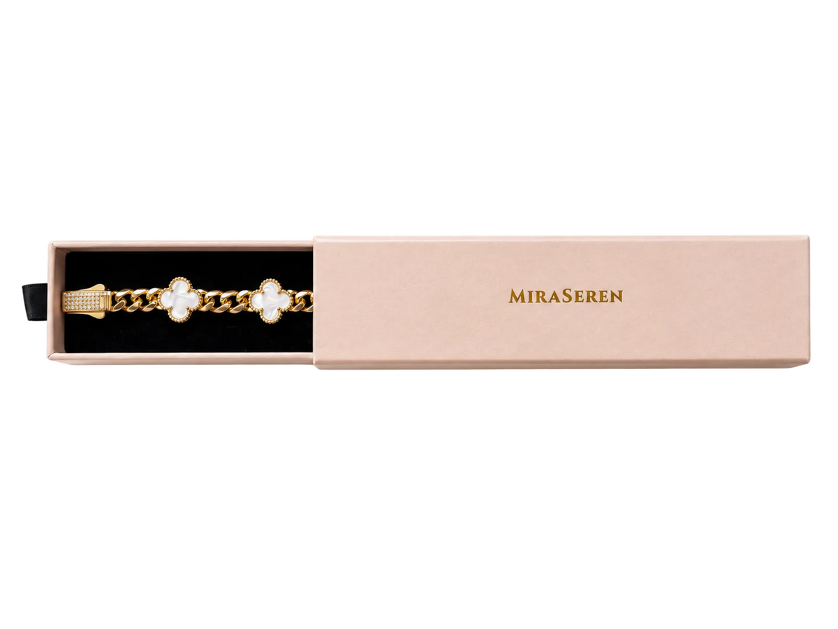 A gold chain bracelet with white floral clover motifs, presented inside an open light pink Miraseren box on a clean white background.