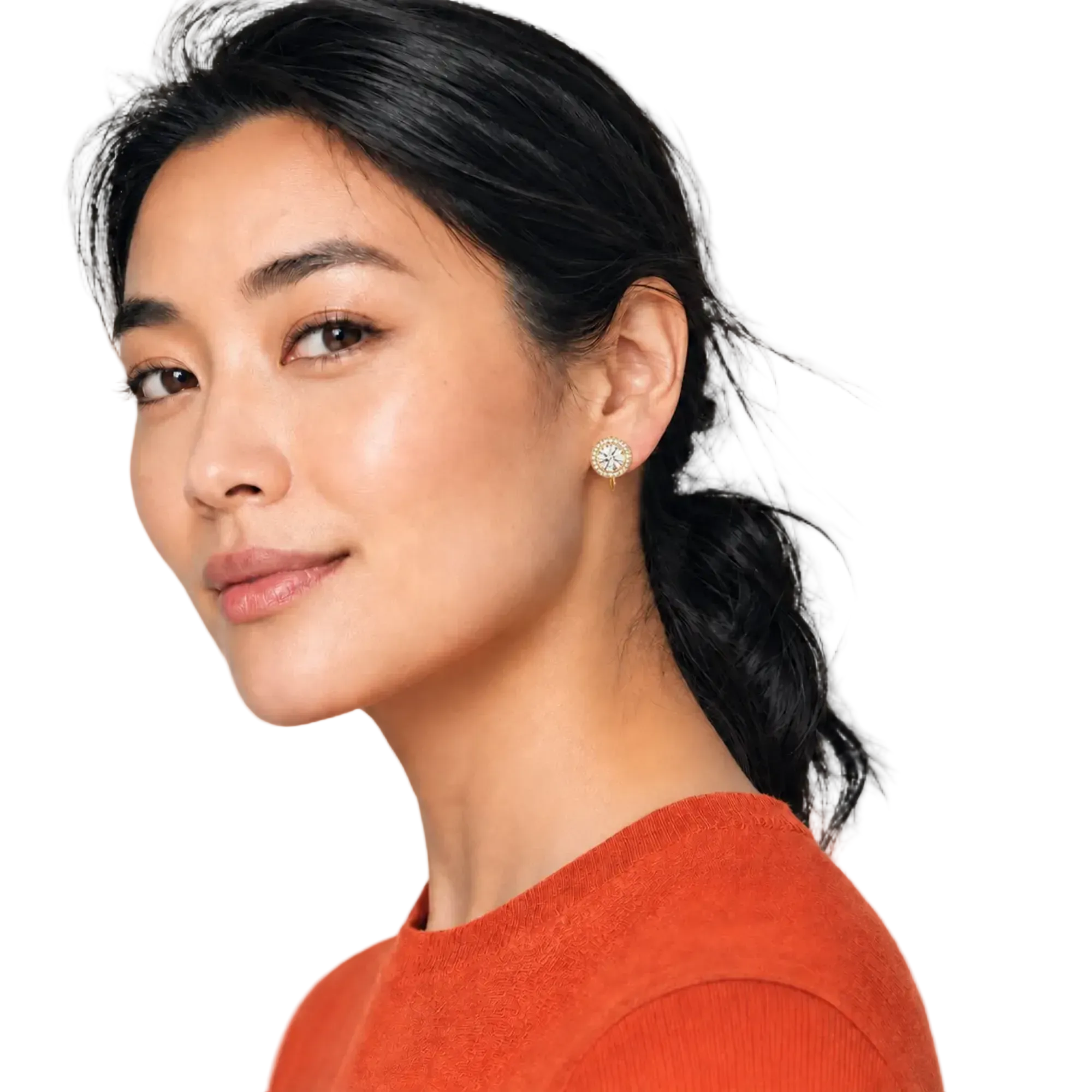 A close-up portrait of a woman with dark hair tied back, wearing a small round gold-toned stud earring with clear stones, against a plain light background.