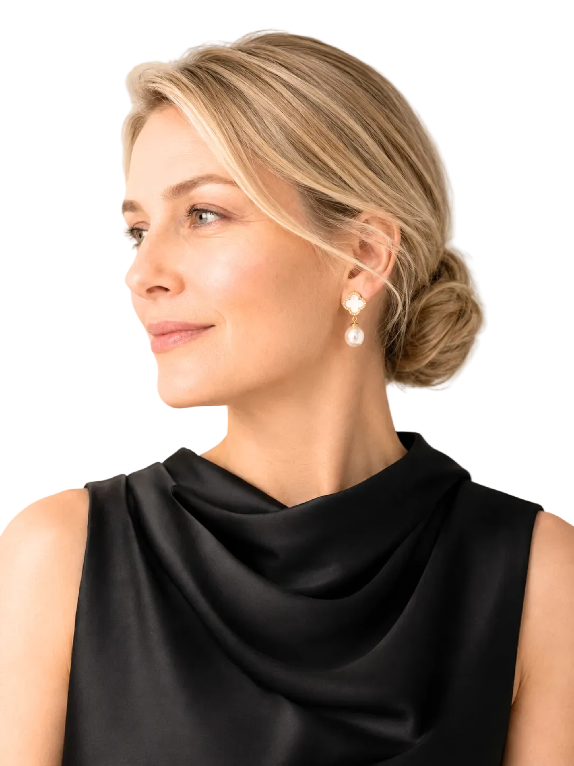 A woman in a black draped sleeveless top wearing a pair of gold and pearl drop earrings, shown in a close-up profile against a soft beige background.