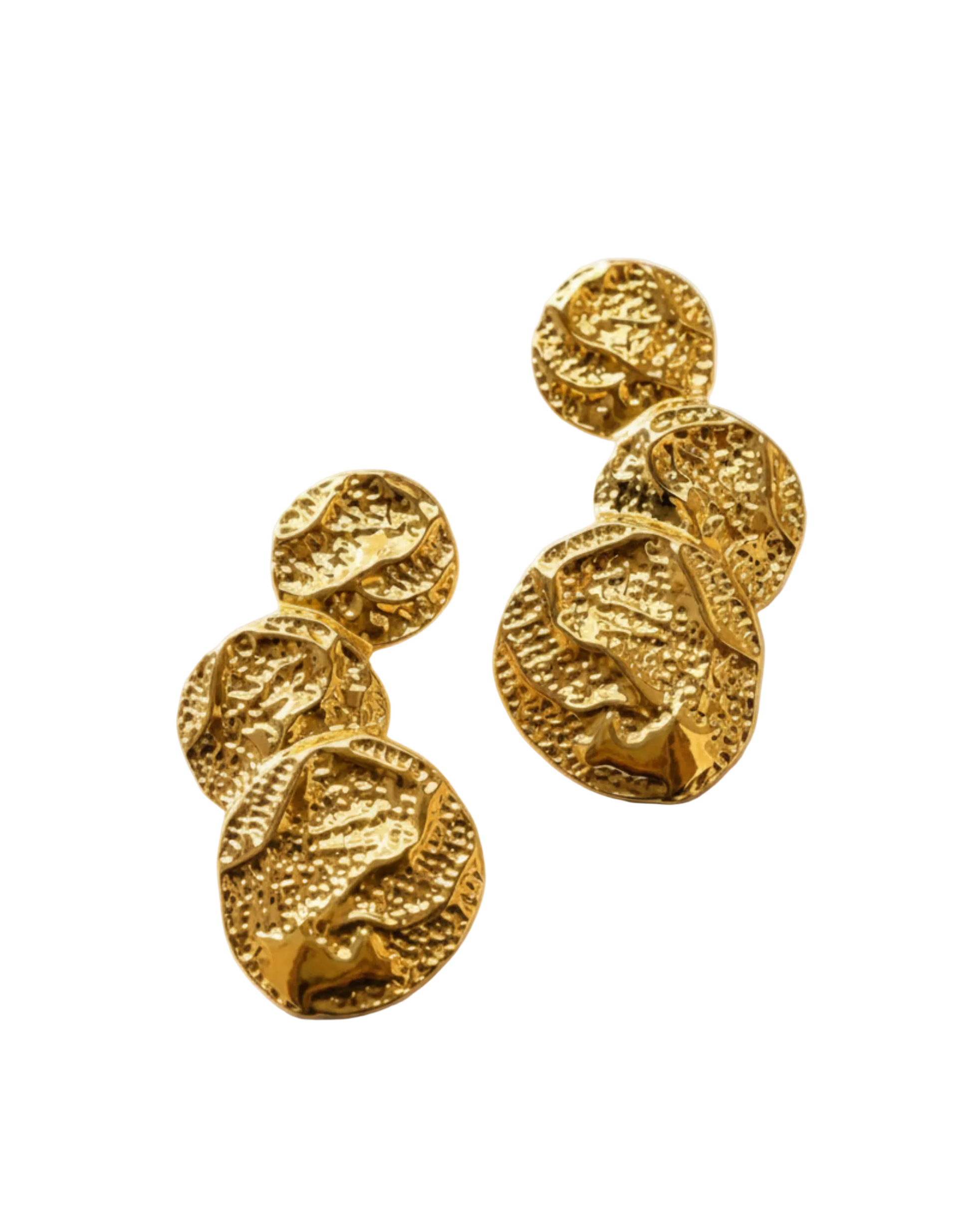 A pair of textured gold drop earrings with organic, overlapping circular shapes, displayed on a warm beige fabric background with soft diagonal shadows.