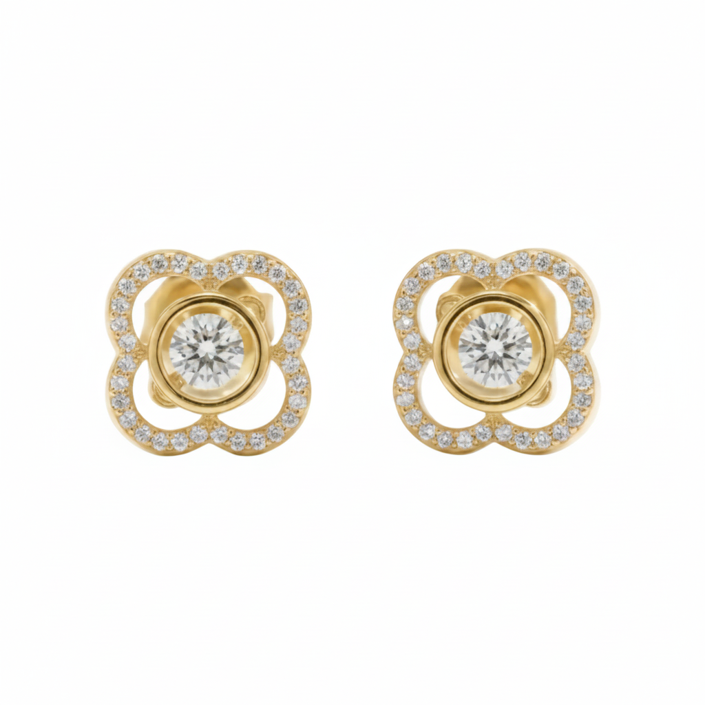 A pair of gold stud earrings with a four-petal flower design, featuring a central round clear gemstone surrounded by a halo of small clear stones, set against a plain white background.
