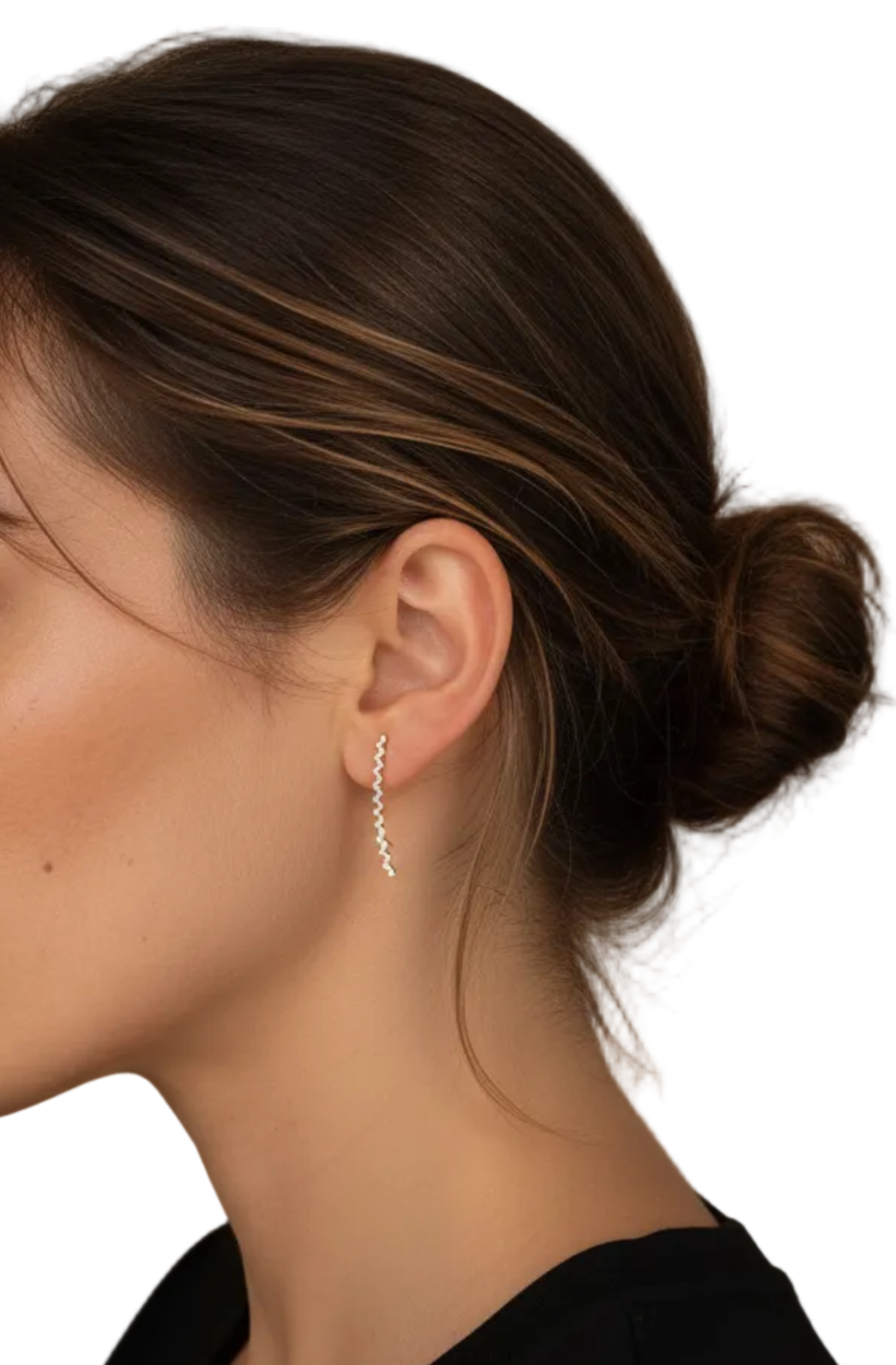 A close-up side profile of a woman wearing a delicate silver dangle earring with a wavy, textured drop, set against an indoor background.