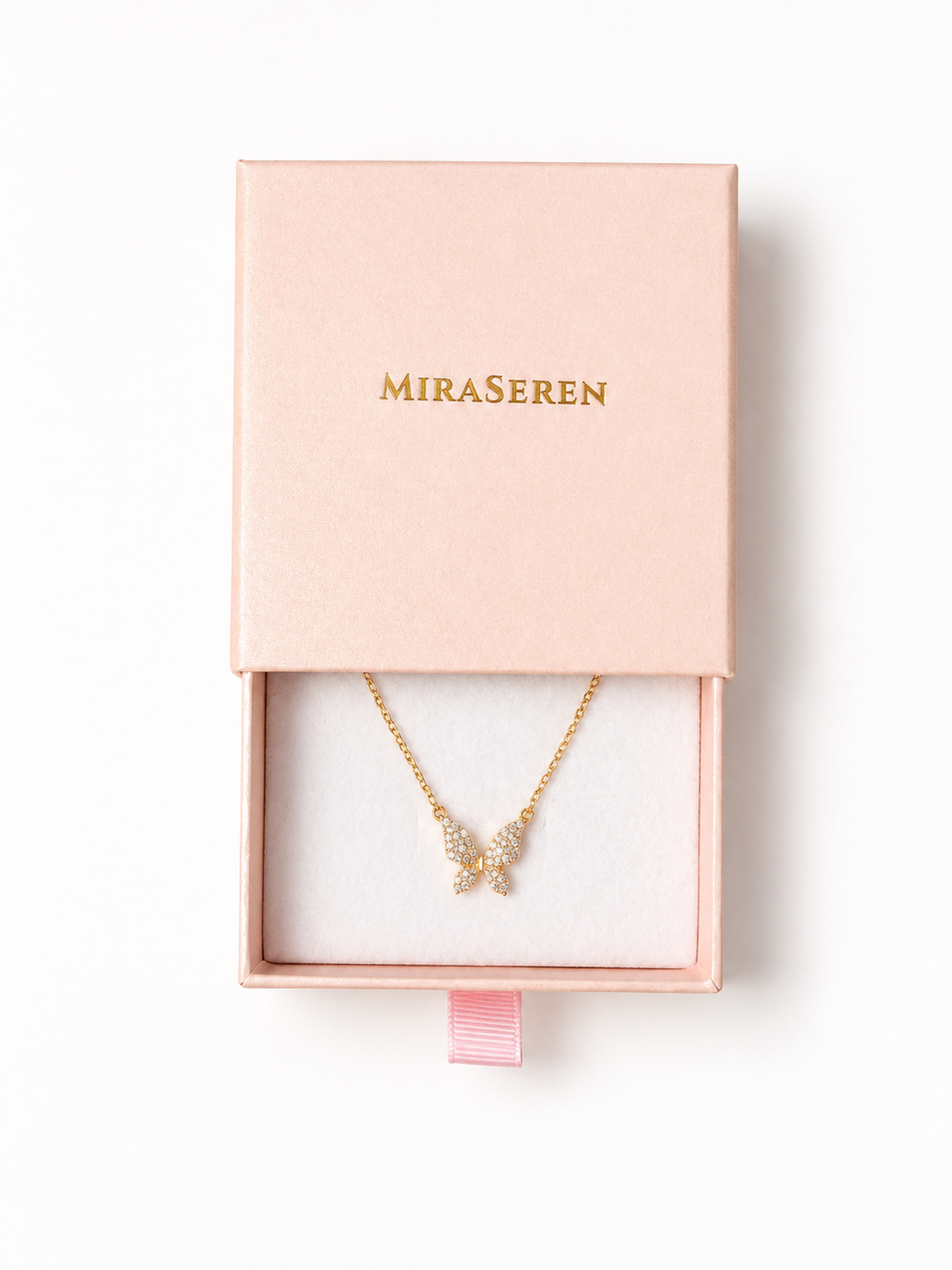 A gold necklace with a butterfly pendant encrusted with small clear stones, presented in an open light pink Miraseren jewelry box on a white background.
