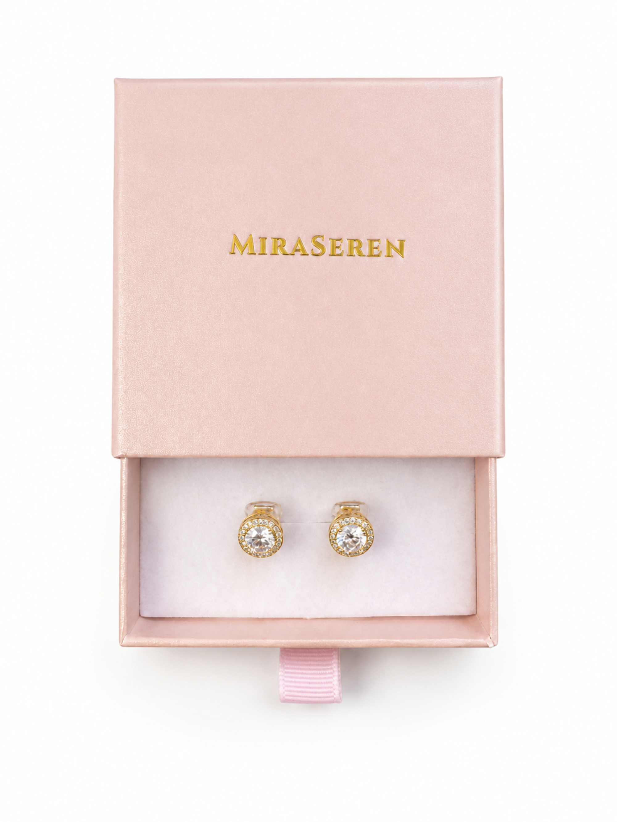 A pair of gold stud earrings with clear gemstones, presented in an open light pink jewelry box with the brand name 'MIRA SEREN' printed in gold on the lid.
