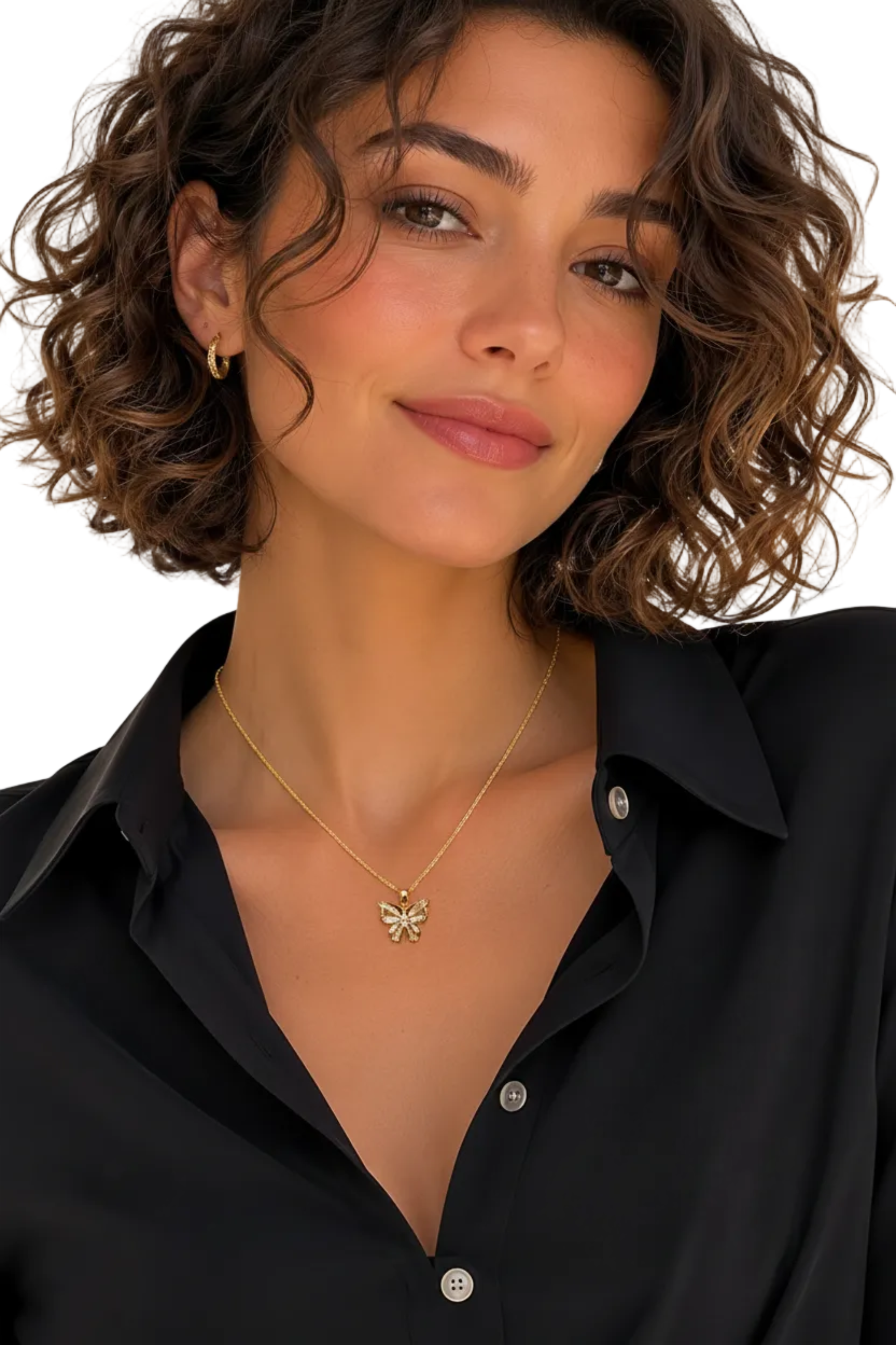 A close-up of a woman with short curly brown hair wearing a delicate gold chain necklace with a small bow-shaped pendant, paired with a black button-down shirt.