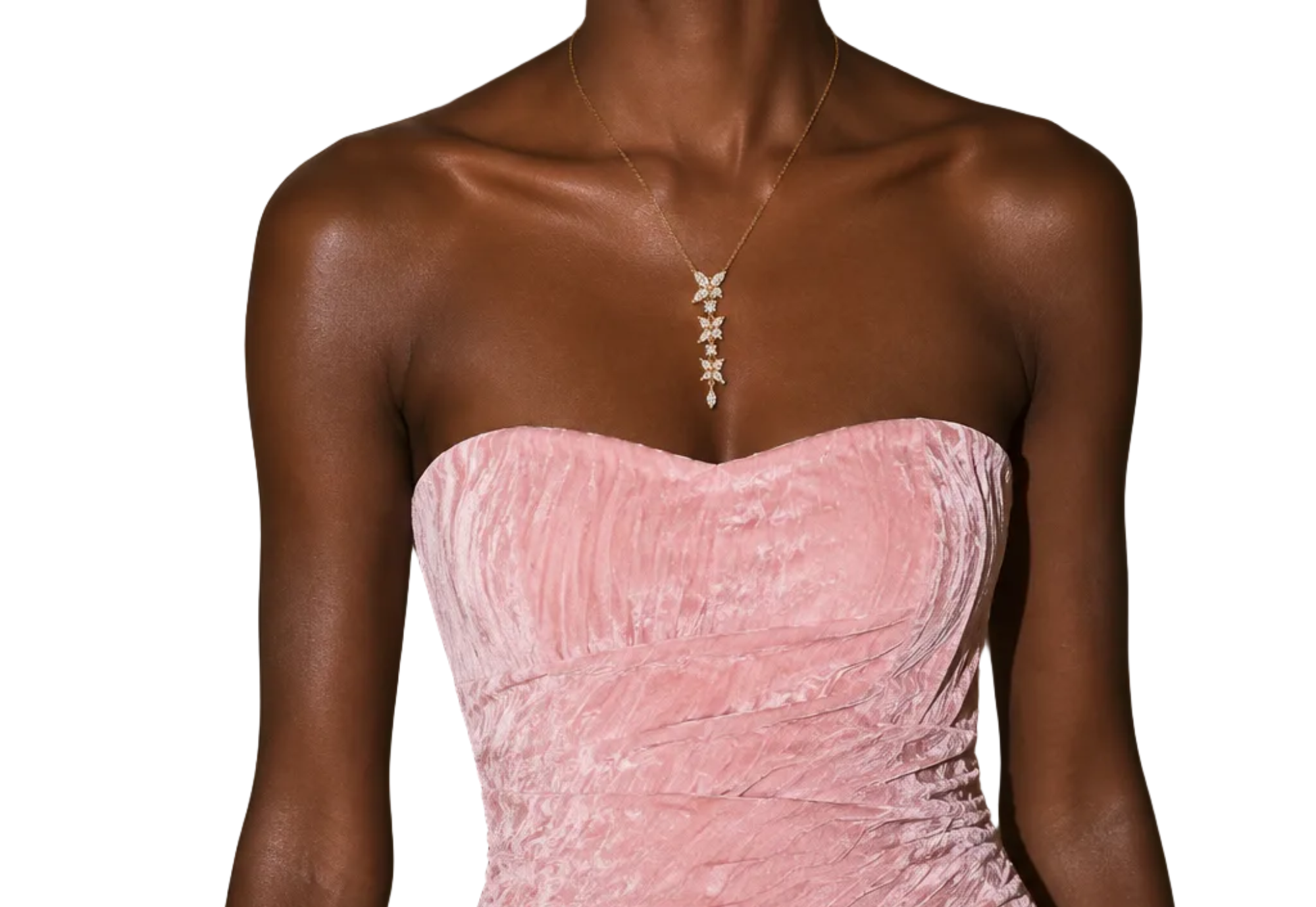 A model wearing a strapless pink velvet mini dress with ruching and a gold butterfly embellishment on the side, holding a matching pink clutch.