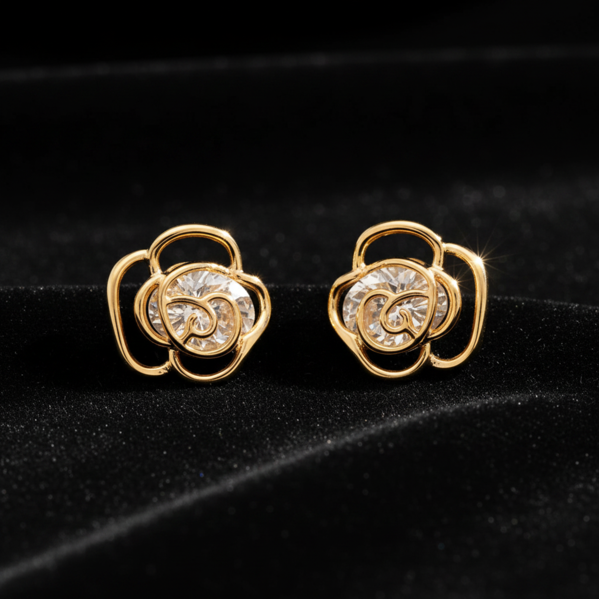 A pair of gold-toned flower-shaped stud earrings with clear faceted gemstones in the center, set against a plain white background.