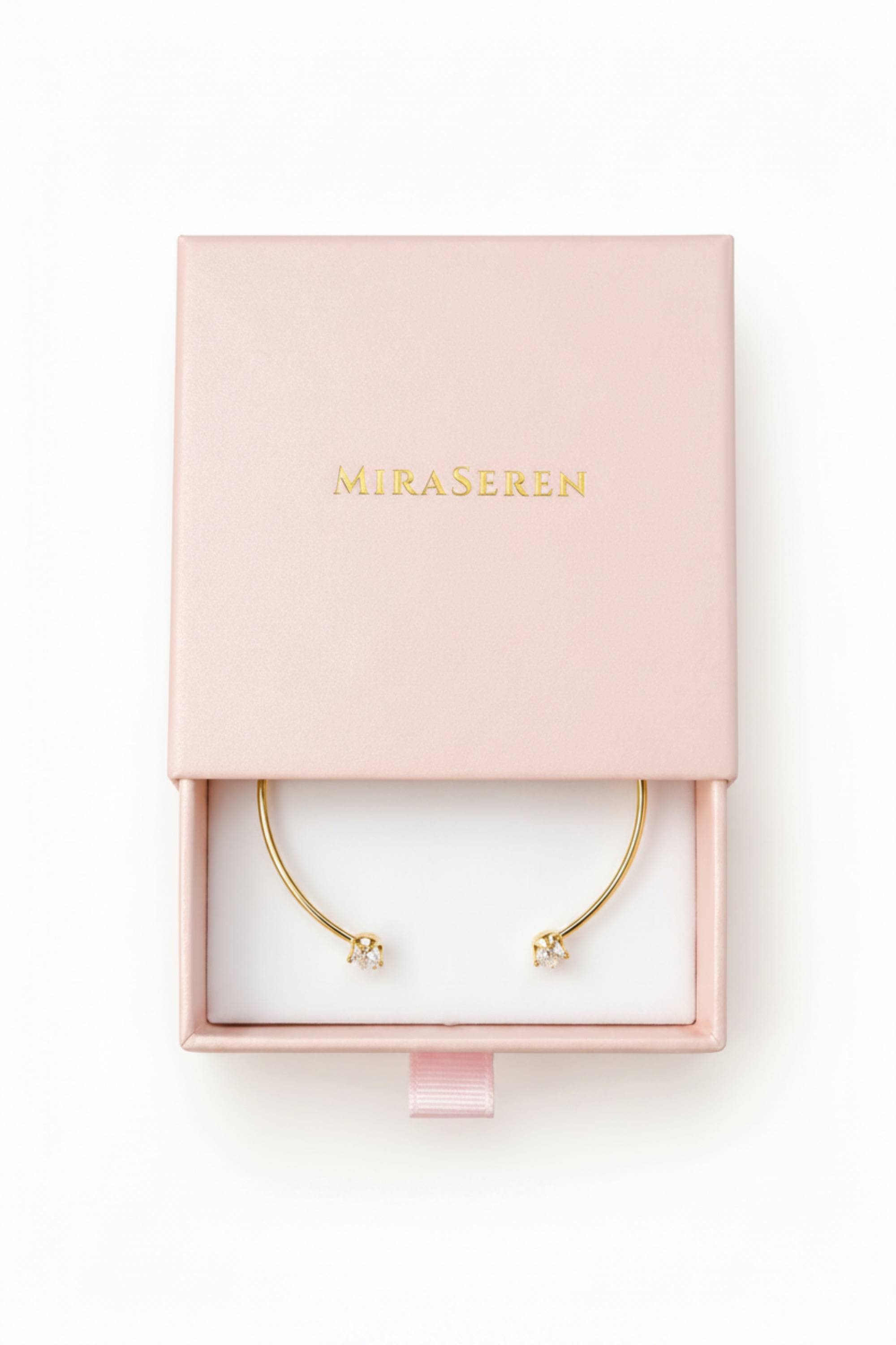 A pair of delicate gold crescent-shaped earrings with small clear crystal accents, presented in an open light pink Miraseren jewelry box on a white background.