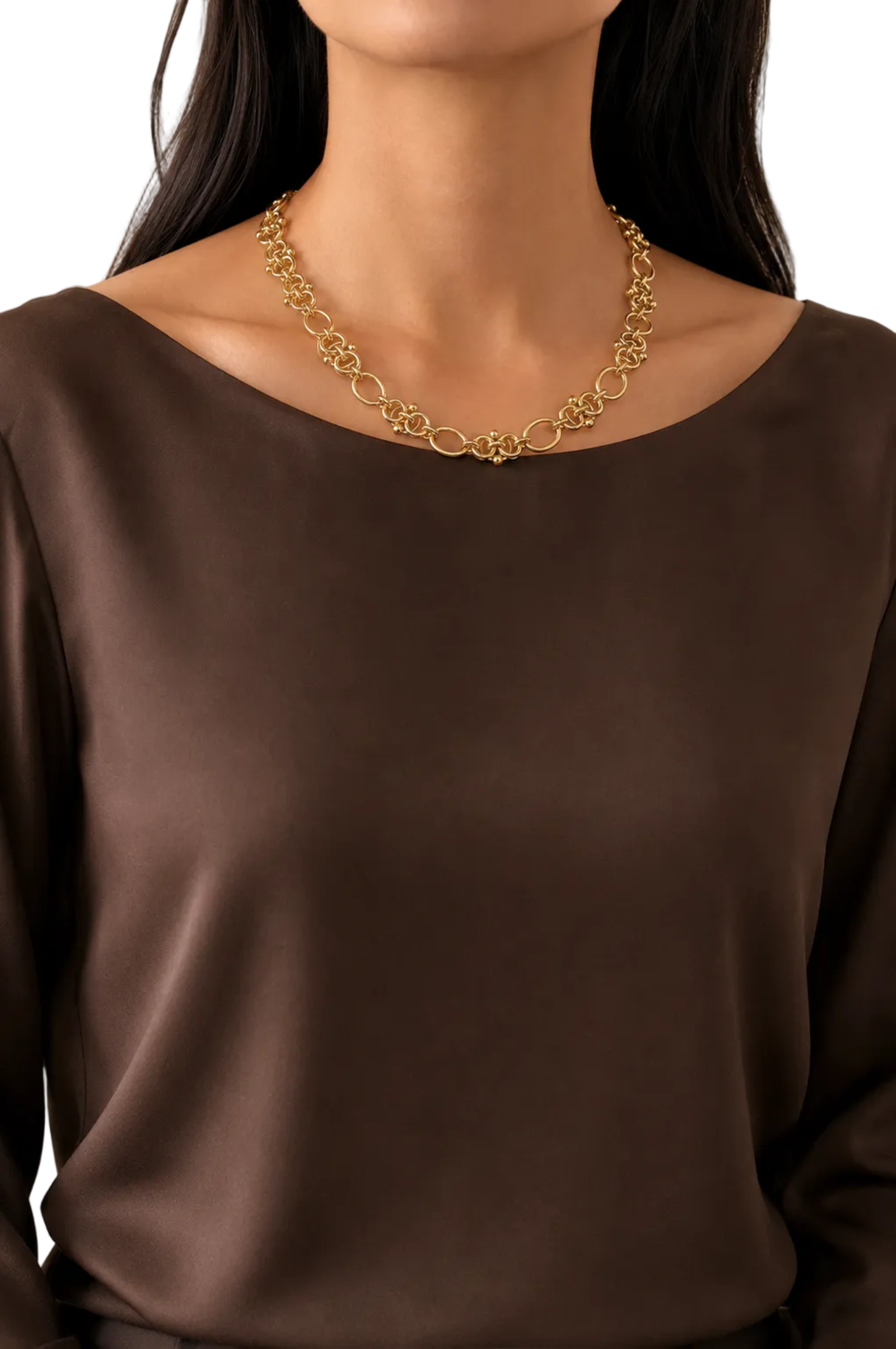 A close-up of a model wearing a gold chain necklace with interlocking circular links, paired with a dark brown satin top against a white background.