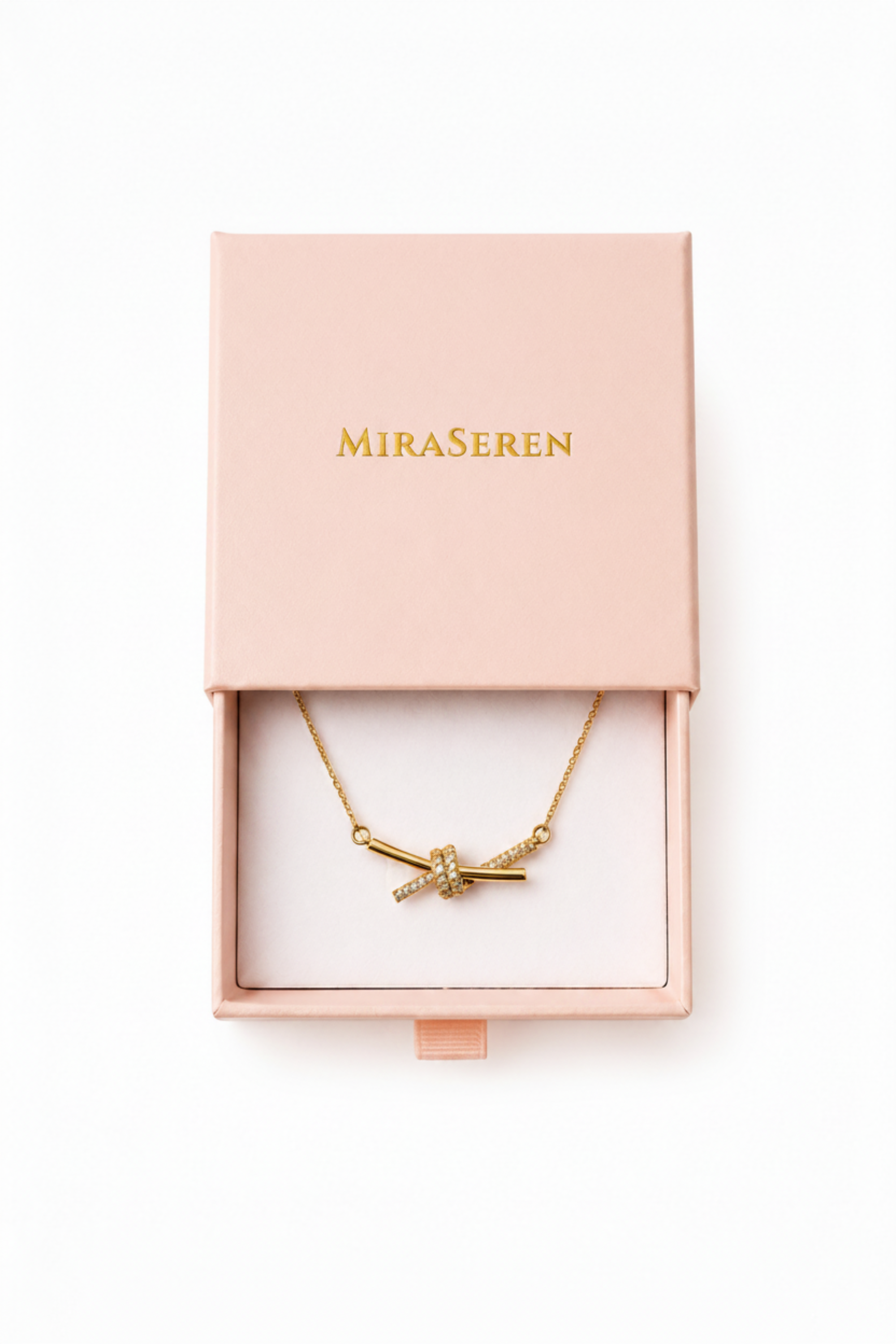 A gold necklace with a bow-shaped pendant displayed inside an open light pink Miraseren jewelry box on a white background.