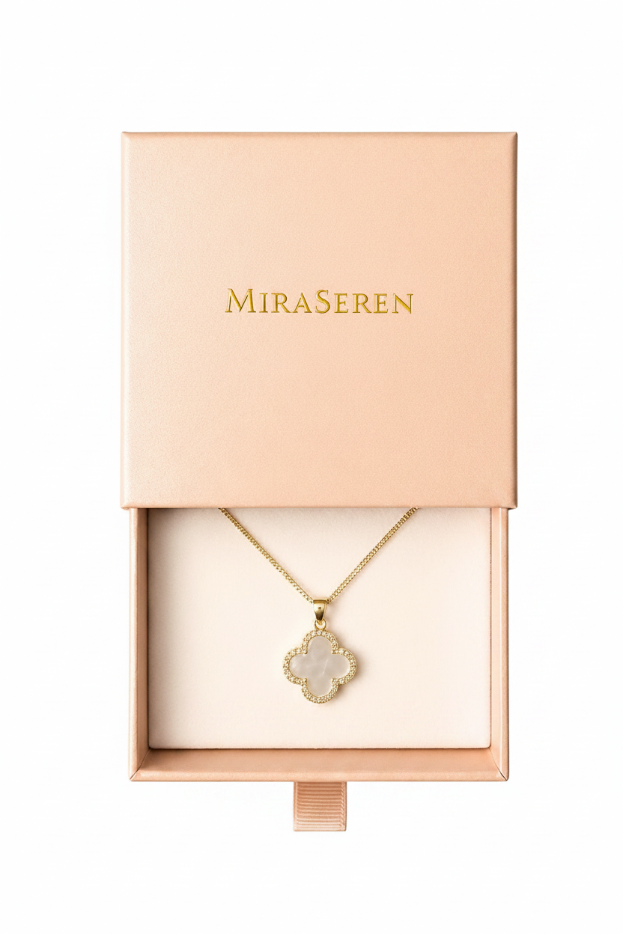 A gold-tone Miraseren necklace with a white marquise-cut stone pendant displayed inside an open blush pink jewelry box.