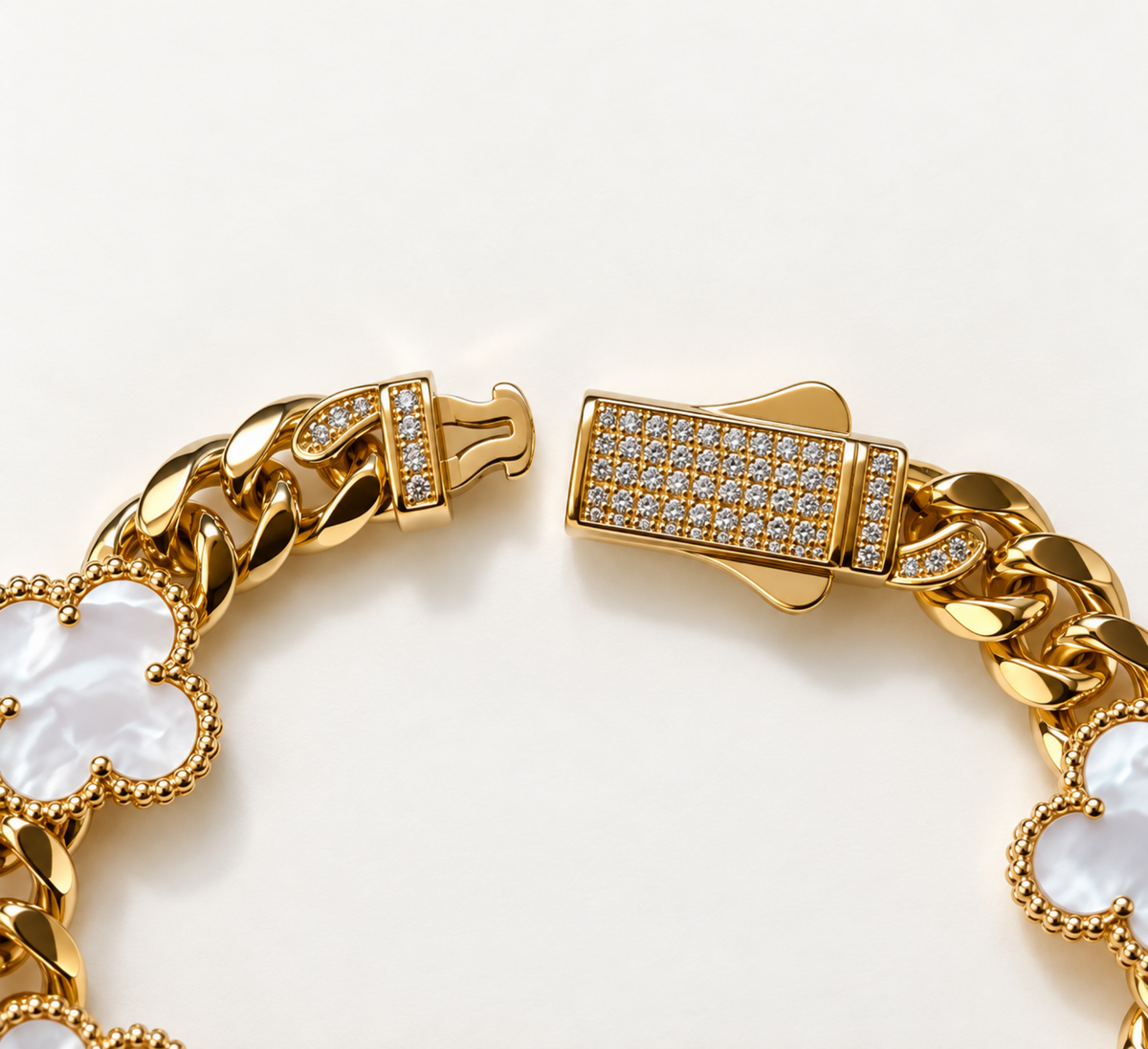 Gold-tone chain bracelet with a clasp covered in small clear stones, featuring white mother-of-pearl four-leaf clover motifs on a white background.
