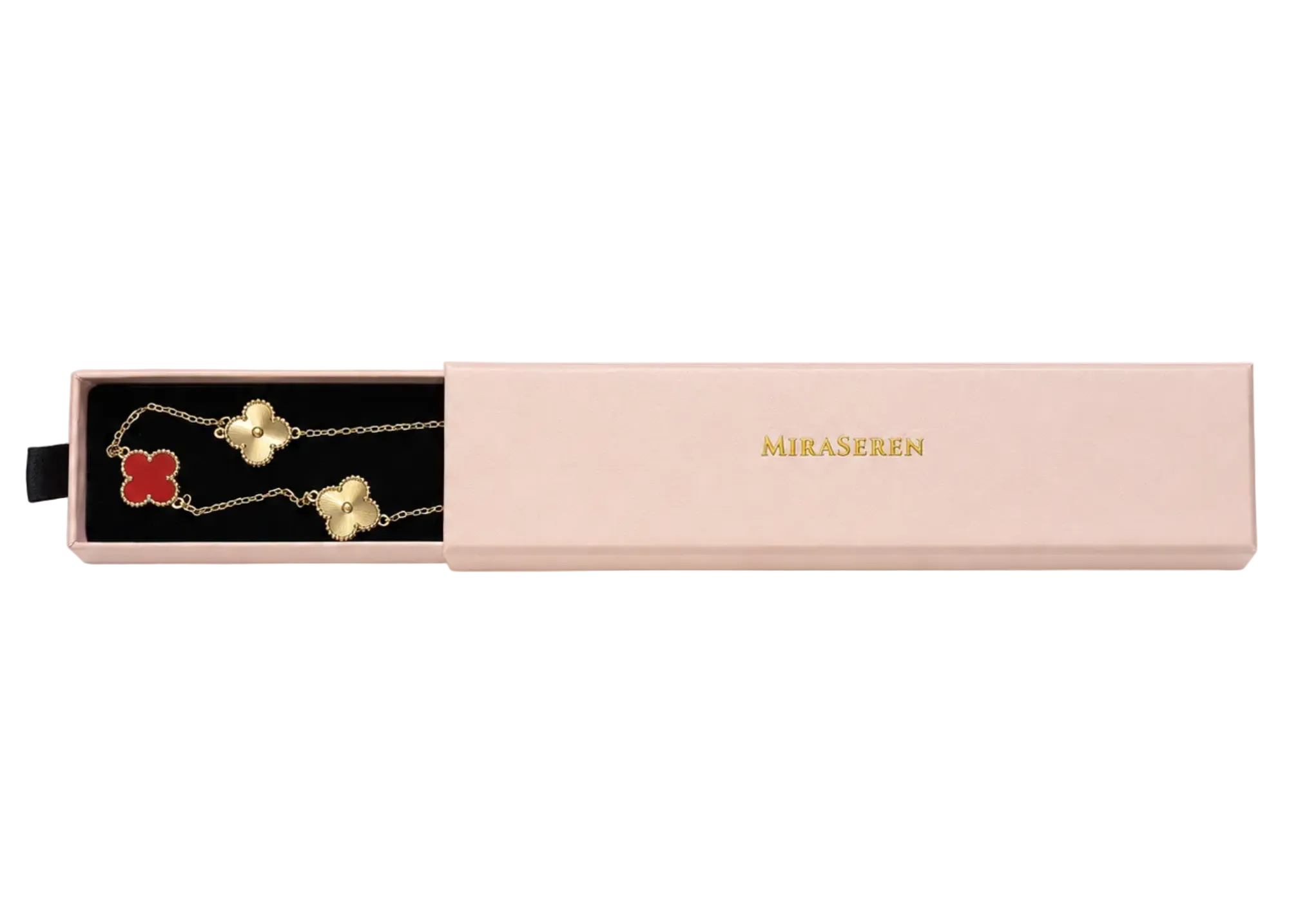 A pink rectangular jewelry gift box on a white background, with the left side slid open to reveal a black-lined compartment holding a gold-tone chain necklace with a red clover and white clover charm. The closed lid shows the brand name 'MIKASEREN' in gold.
