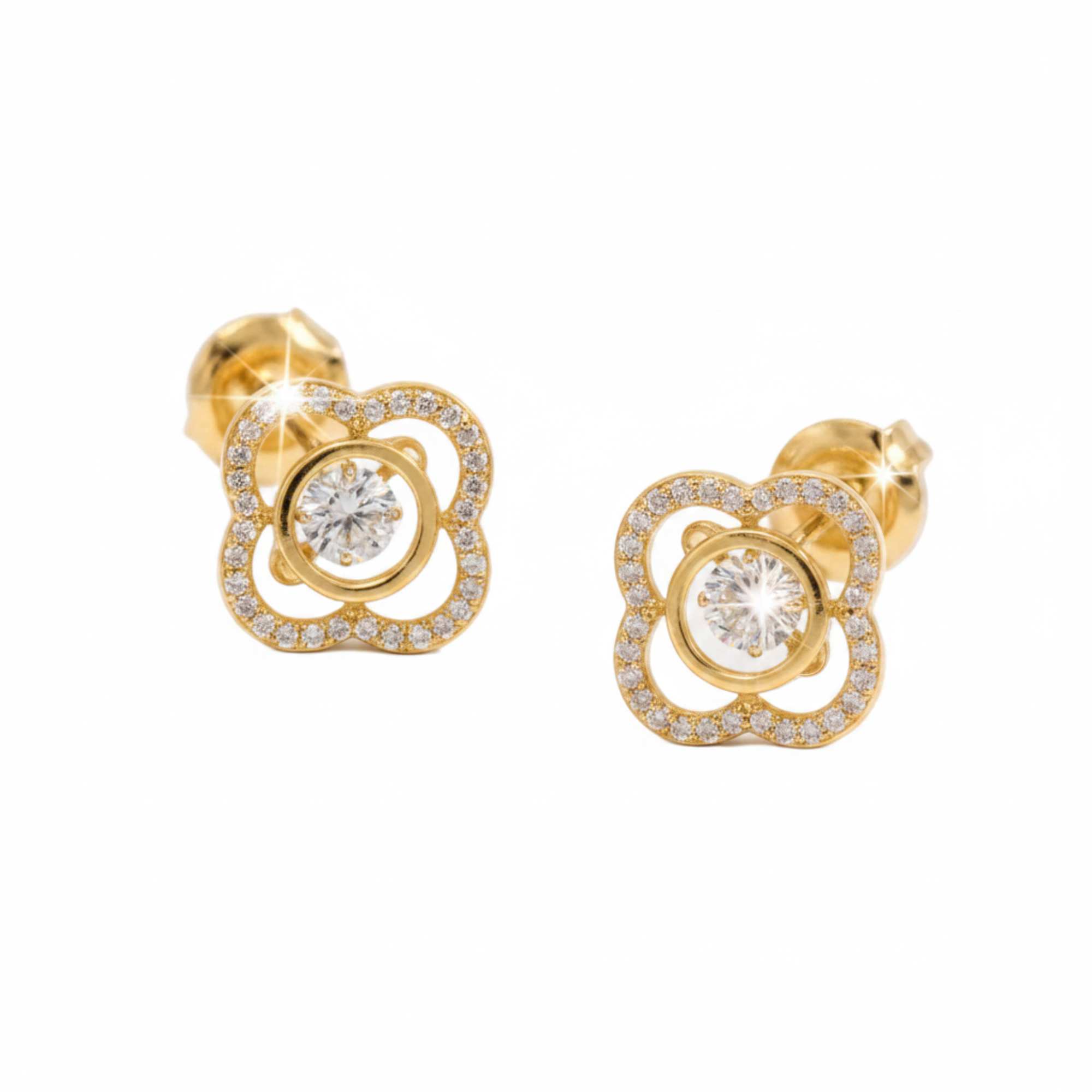 A pair of gold flower-shaped stud earrings with a central round clear gemstone surrounded by a halo of small clear stones, set against a plain white background.